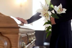 woman with flowers and coffin at funeral